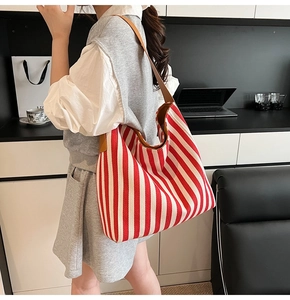 Large red and white striped canvas tote bag with brown leather straps shown on a shoulder