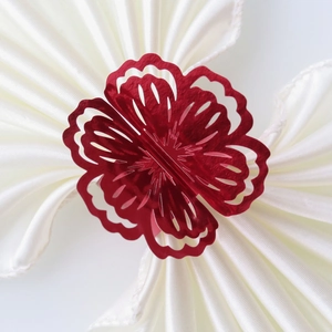 Macro shot of a wine red floral napkin ring on a white pleated satin fabric base
