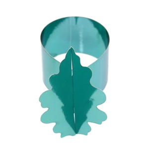 Détail du rond de serviette en métal vert avec motif de feuilles sur fond blanc