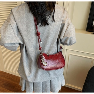Detail of red wrinkled leather shoulder bag with silver rabbit charm and knot strap
