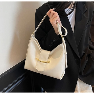 Detail view of cream hobo shoulder bag with a gold crescent buckle on a black blazer