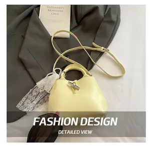 Close-up of pale yellow bucket bag featuring a metallic bamboo clasp and lace details