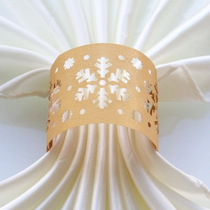 Close-up of golden laser-cut snowflake paper napkin ring with elegant hollow pattern