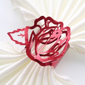 Detailed view of a red metallic rose napkin ring with intricate hollowed-out petals