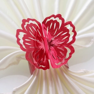 Detail of red glitter flower napkin ring with hollow laser-cut design on white fabric