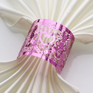 Detail of pink glitter laser-cut napkin ring with heart pattern on white silk napkin