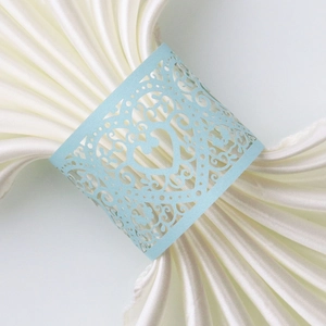 Macro detail of laser-cut light blue heart napkin ring on white satin fabric