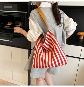 Red and white striped canvas tote bag with brown leather straps in a home kitchen setting