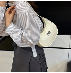 Detail of cream hobo bag showing crocodile texture and silver plaque on shoulder strap