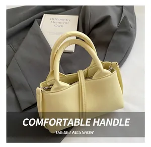 Detail shot of a buttery yellow leather handbag with padded bubble handle and metal buckle