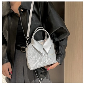 Detail of silver shirt-shaped handbag with marble texture and metallic finish on model