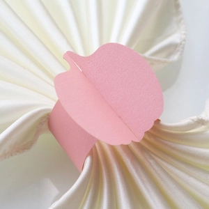 Close-up of pink paper pumpkin leaf napkin ring on beige satin fabric for table decor