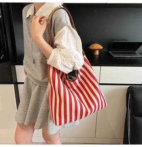 Detail of red and white striped canvas tote bag with brown leather shoulder straps