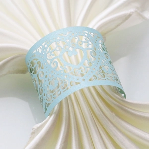 Detail of light blue laser-cut paper napkin ring with heart design and floral patterns