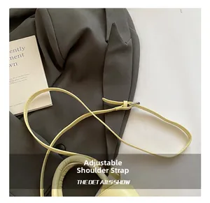 Detail of adjustable leather shoulder strap with metal buckle on light yellow handbag