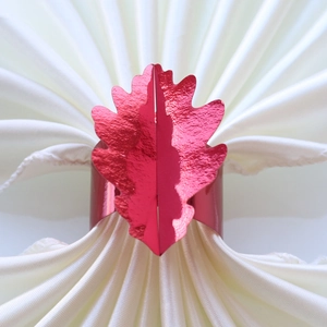 Détail d'un rond de serviette en forme de feuille rouge avec texture métallique