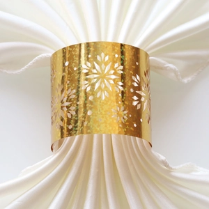 Detail view of laser-cut gold snowflake napkin ring with shimmering finish on satin