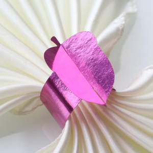 Close-up of elegant leaf-shaped rose red metallic napkin ring for formal dining decor