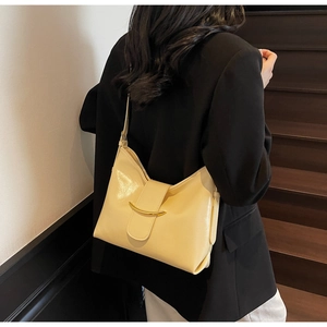 Detail of cream yellow leather hobo bag featuring a gold crescent metal clasp and strap