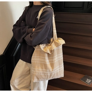 Gros plan du sac cabas en toile Vichy marron avec motifs tissés sur escalier en bois