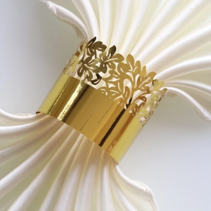 Detailed close-up of golden leaf napkin ring on white fabric for elegant wedding table decor