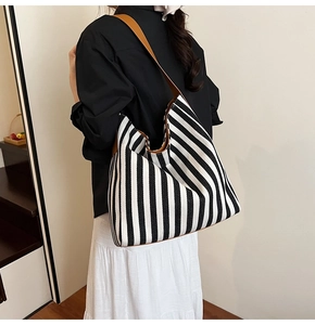 Detail of a striped canvas tote bag with brown leather handles and spacious interior