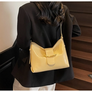 Beige shoulder bag with gold crescent buckle detail on model with black blazer