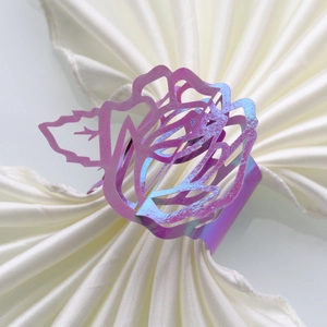 Close-up of iridescent purple metal napkin ring featuring hollow rose flower design