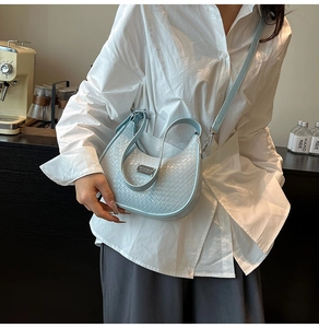 Detail of light blue woven texture on a crescent shoulder bag with silver hardware