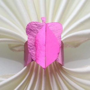Detail of pink purple metallic acorn napkin ring on a white silk table napkin