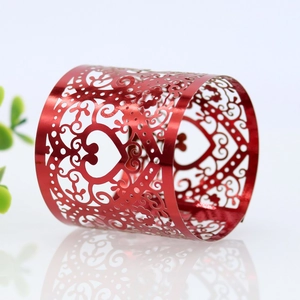 Close-up of red metal napkin ring featuring laser-cut heart and vine pattern