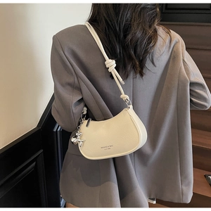 Detail of off-white crescent bag with knotted strap and silver balloon dog charm