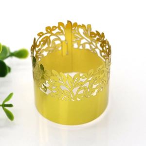 Detail of a golden cutout napkin ring with intricate leaf patterns for party decor