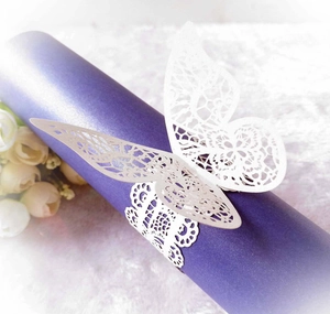 Detail of white laser-cut paper butterfly napkin ring with intricate lace pattern