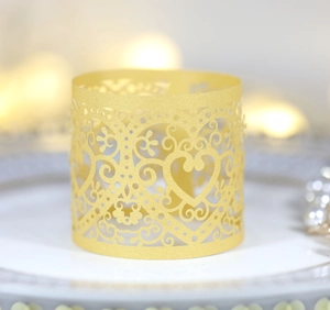 Macro shot of gold laser-cut heart paper napkin ring on a white plate with bokeh lights