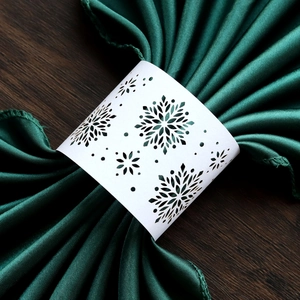 Macro shot of laser-cut white paper napkin ring featuring a delicate snowflake design