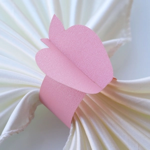 Close-up of pink pearlescent butterfly paper napkin ring on a white silk napkin