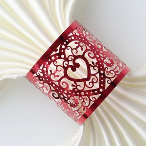 Elegant red laser-cut heart napkin ring on white satin cloth for wedding table decor