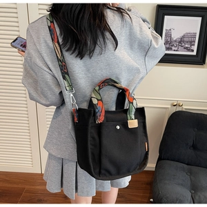 Detail of black canvas tote bag featuring colorful jacquard ethnic pattern shoulder straps