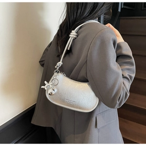 Detail of silver metallic hobo bag with knotted strap and butterfly charm accessory