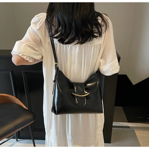 Detail of black glossy leather crescent shoulder bag with golden metallic buckle
