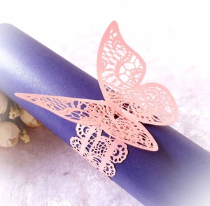 Macro detail of laser-cut pink paper butterfly napkin ring with hollow lace pattern