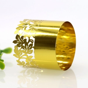 Close-up of golden napkin ring featuring delicate hollowed leaf patterns for weddings