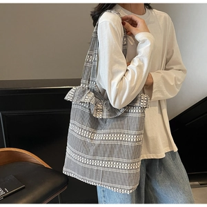 Détail d'un sac cabas en toile vichy noir et blanc avec bords volantés et broderies