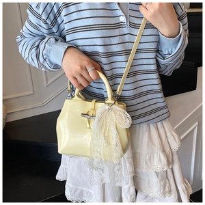 Detail of yellow leather handbag with bamboo buckle and pearl lace bow charm accent