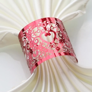 Macro shot of red heart napkin ring with laser-cut hollow patterns on white satin