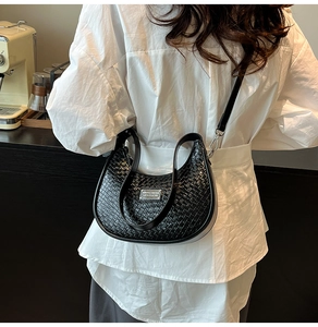 Detail of black woven crescent moon bag with silver metal plate and textured finish
