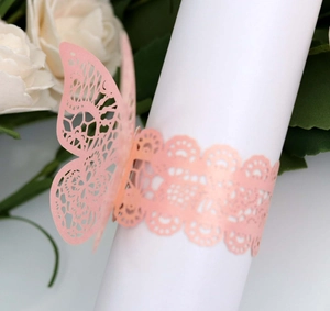 Detail of pink laser-cut butterfly napkin ring with intricate lace pattern for wedding