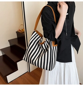 Detail of black and white striped canvas tote bag with brown leather shoulder strap