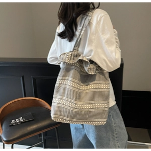 Détail d'un grand sac cabas en toile à damier noir et blanc porté à l'épaule